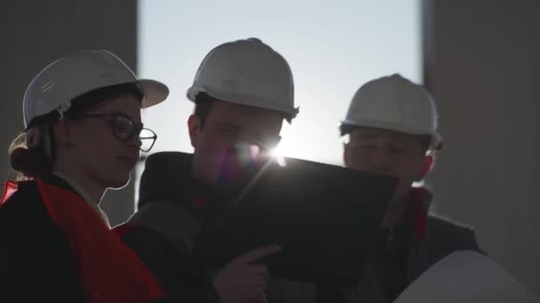 Bâtiment, l'équipe de spécialistes de la construction dans les casques de protection discute du nouveau projet de construction sur le site de développement — Video