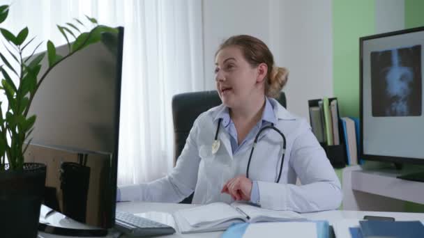 Лікар онлайн, усміхнений терапевт медичний працівник радить пацієнту через відеозв'язок і дає рекомендації для одужання з офісу — стокове відео