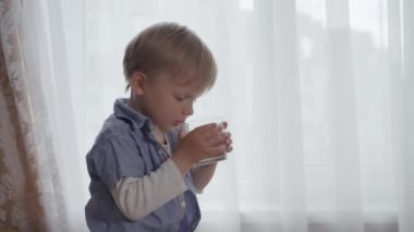 Şefkatli anne sağlıklı erkek çocuğuna bir bardak temiz içme suyu verir.