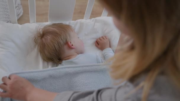 Vrolijke vrouw genieten moederschap strelen geliefde knap mannelijk kind slapen zoet in een zacht comfortabel beddengoed in wieg — Stockvideo