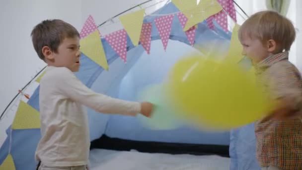 Детские отношения, милые дети братья весело играть с воздушными шарами возле wigwam — стоковое видео