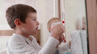 Erkek çocuklar temizlikçilere temizlik için yardım eder ve aynayı deterjan ve bezle kirden silerler.