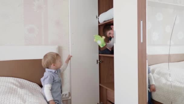 Despreocupados niños alegres se divierten jugando en un armario con un juguete en la mano — Vídeo de stock