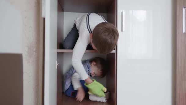 Attractive little carefree children enjoy games in closet and have fun playing hide and seek — Stock Video