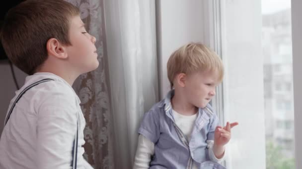 Pequeños niños lindos charlando entre sí mirando por la ventana disfrutando del descanso en la habitación — Vídeos de Stock