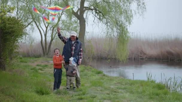 Familia, amar anciano abuelo hombre juega cuidadosamente con sus queridos nietos chicos lanzamiento de cometa — Vídeo de stock