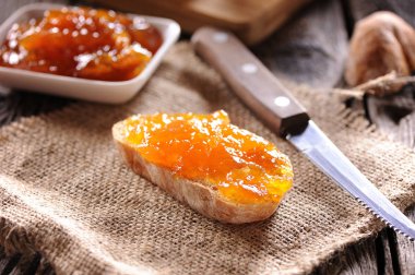 ekmek ve ahşap masa üzerinde turuncu ev yapımı reçel