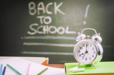 Okul kitapları, elma ve masa saati