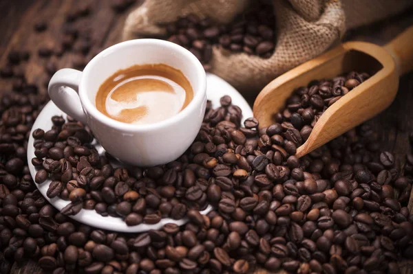 Koffie beker close-up over donkere gebrande koffiebonen — Stockfoto