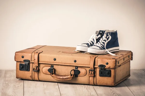Sneakers and an old brown suitcase with a retro effect — Stock Photo, Image