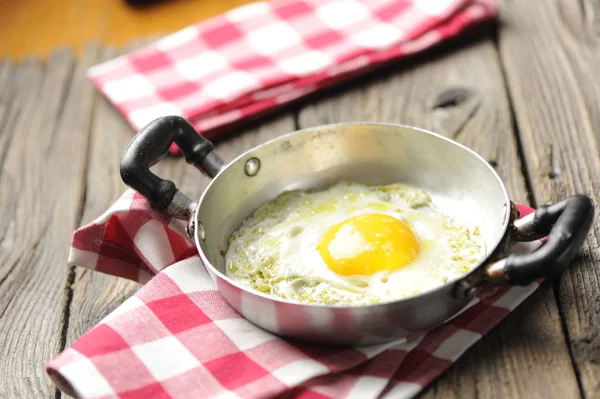 Scrambled eggs in an iron pan on the rustic wooden table — Stock Photo, Image