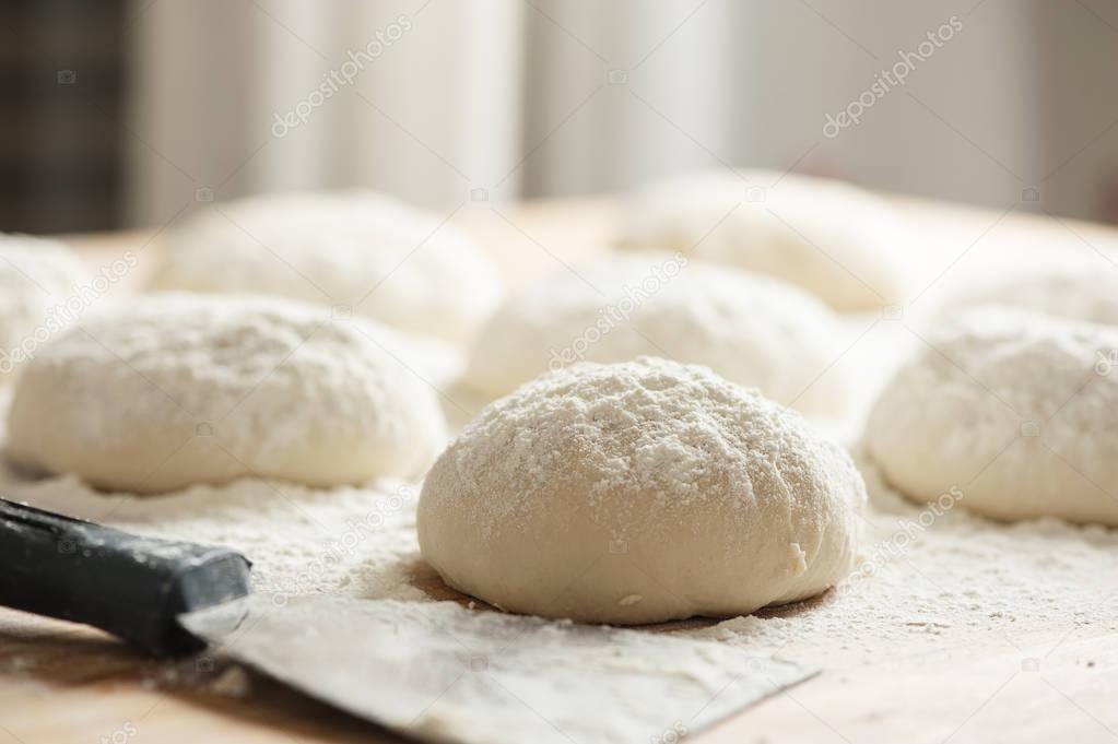 balls of dough covered with wheat flour ready for baking