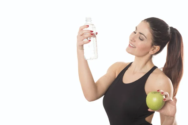Jeune femme souriante tenant une bouteille d'eau et de pomme — Photo