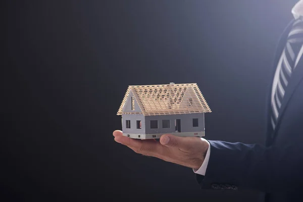 Бизнесмен держит образцовый дом в ладони — стоковое фото