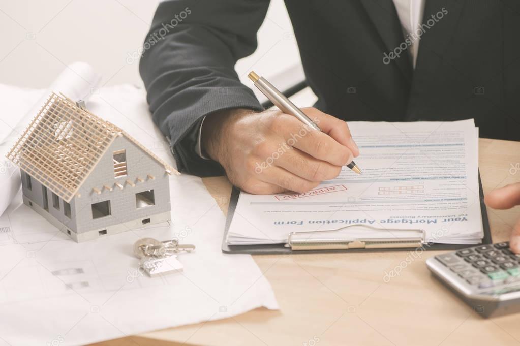  Businessman signing a mortgage  contract  of a sale for a new h