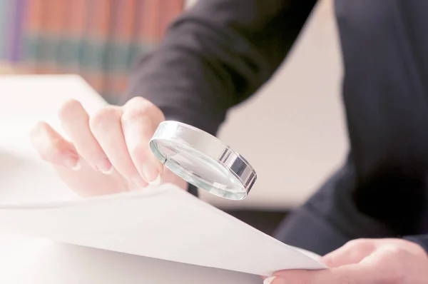 Primer plano de joven empresario mano examinando factura con lupa — Foto de Stock