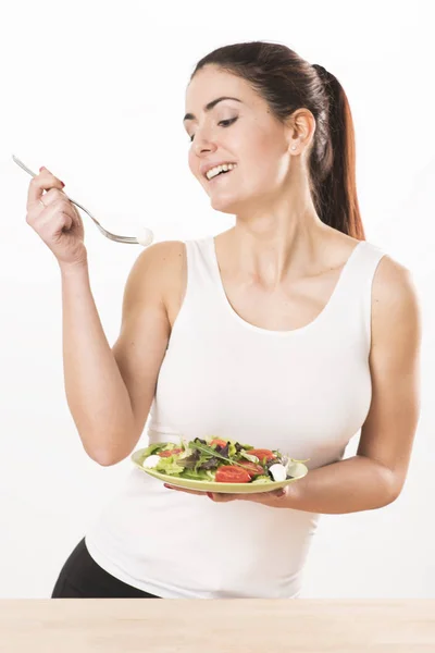 Νεαρή γυναίκα τρώει σαλάτα και κρατώντας μια ανάμικτη σαλάτα — Φωτογραφία Αρχείου