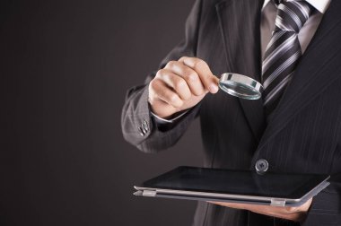 teknoloji, internet ve iş kavramı - Büyüteç tablet pc bilgisayar üzerinde tutan işadamı