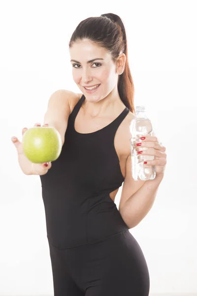 Joven mujer caucásica sosteniendo una botella de agua y una manzana sobre fondo blanco —  Fotos de Stock