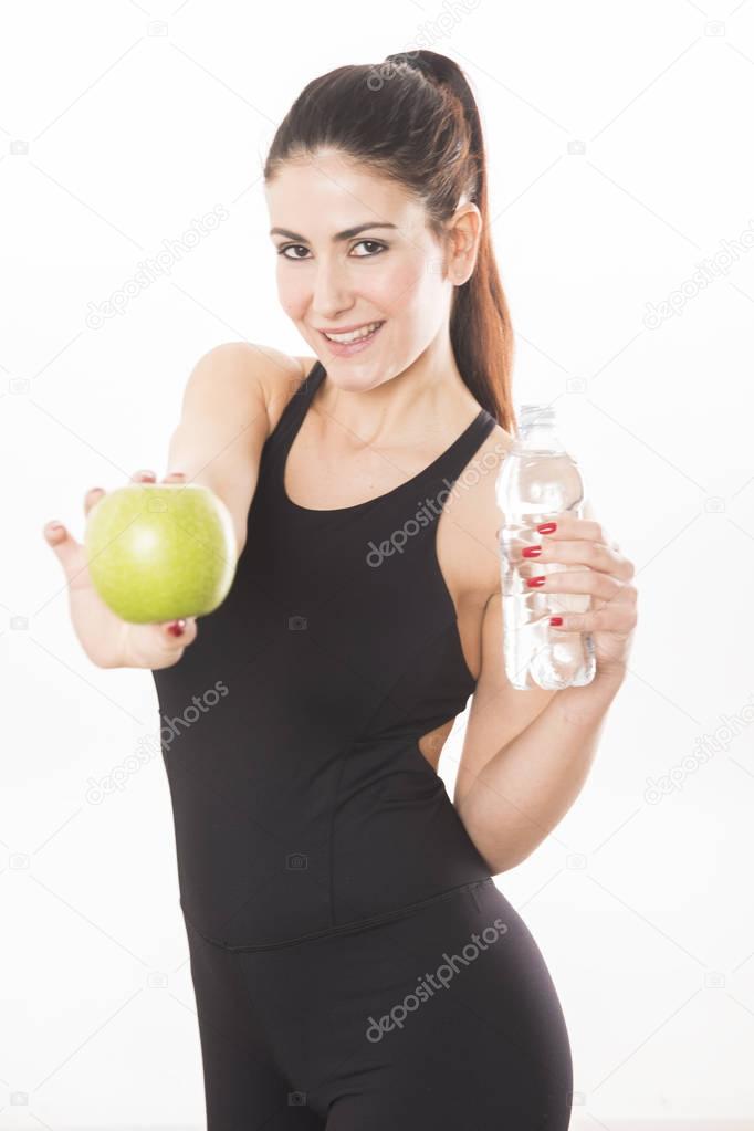 Young caucasian woman holding a bottle of water and an apple over white background