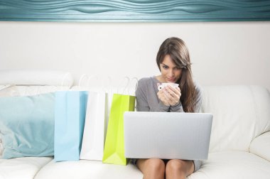 Genç erkek ile laptop beyaz kanepede otururken kahve içer