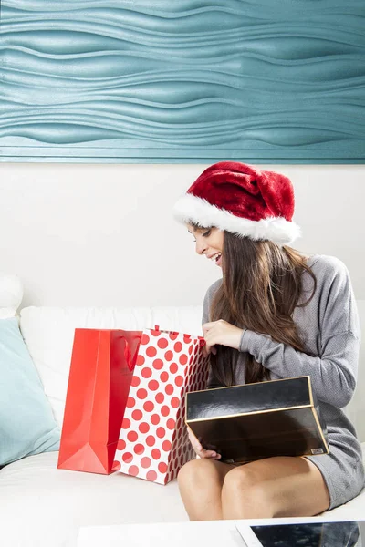 Menina beleza abrindo caixa de presente presente sentado no sofá em casa — Fotografia de Stock