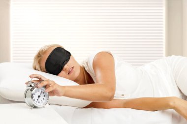 Evdeki yatak odasında uyuyan genç kadın ve çalar saat.