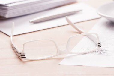 Gözlük, zarf kağıt ve bir kalem