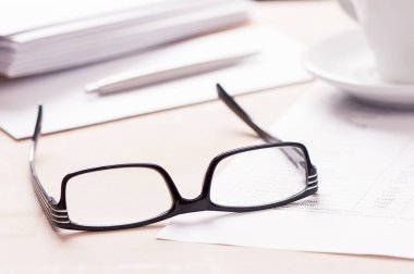 Gözlük, zarf kağıt ve bir kalem