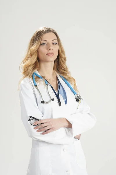 Female doctor in white surgical coat and stethoscope standing isolated on white background — Stock Photo, Image