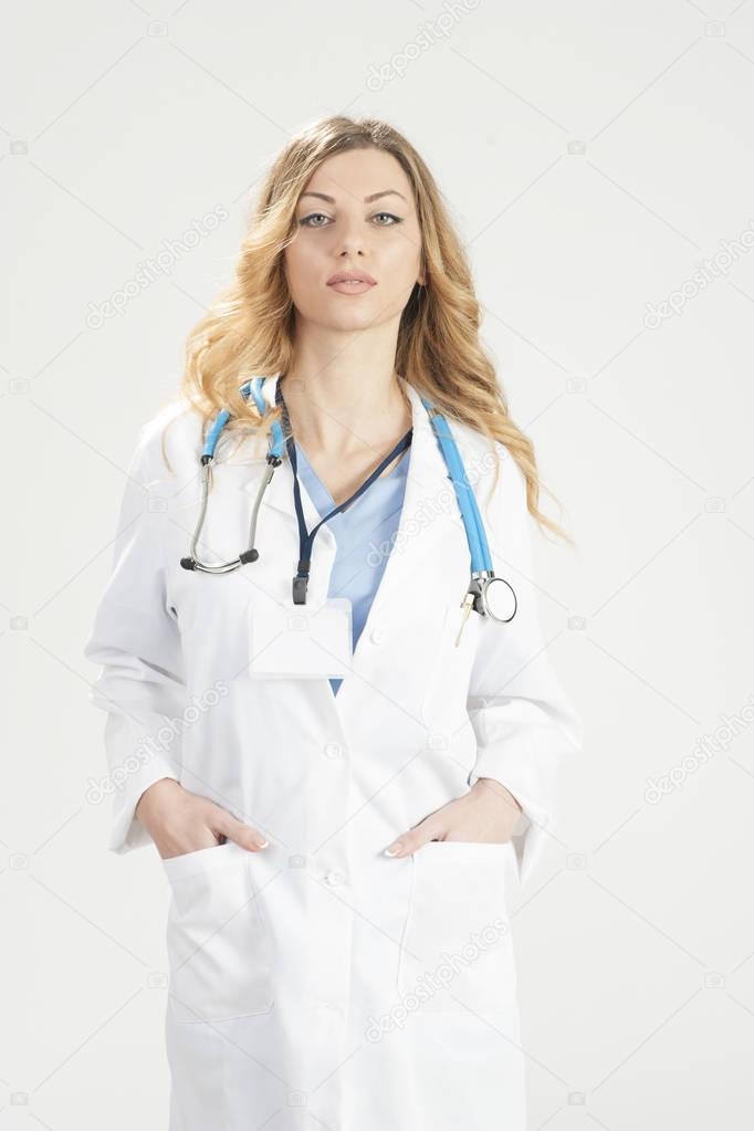 Female doctor in white surgical coat and stethoscope standing isolated on white background