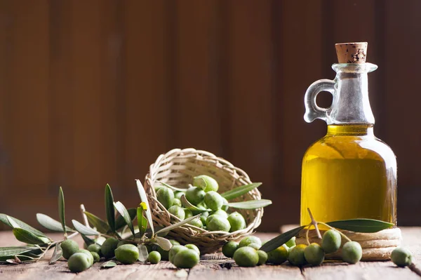 Aceite de oliva y aceitunas sobre mesa rústica de madera — Foto de Stock