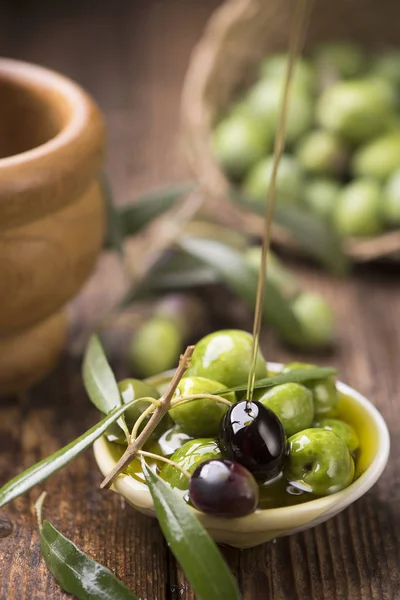 Flaska hälla virgin olivolja i en skål på nära håll — Stockfoto