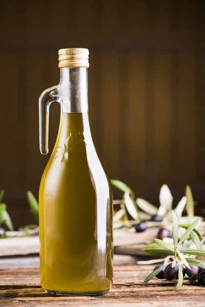 Aceite de oliva y aceitunas sobre mesa rústica de madera — Foto de Stock
