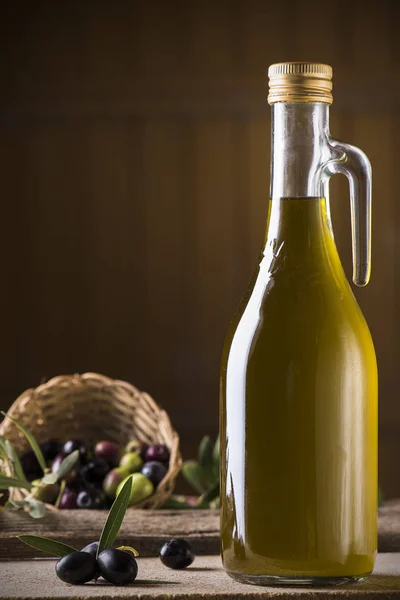 Aceite de oliva y aceitunas sobre mesa rústica de madera — Foto de Stock