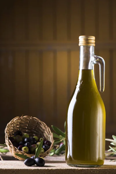 Aceite de oliva y aceitunas sobre mesa rústica de madera — Foto de Stock