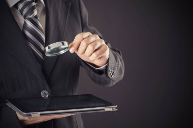 Büyüteç ve dijital tablet kavramı holding iş adamı