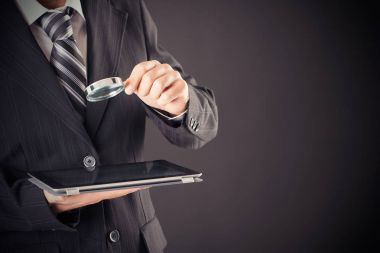 Büyüteç ve dijital tablet kavramı holding iş adamı