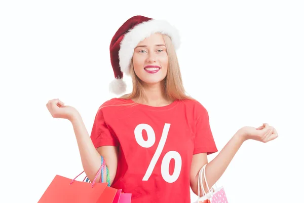 Happy young woman with santa hat carrying shopping bags — Stock Photo, Image
