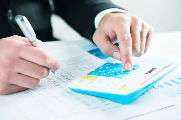 Empresario sentado en el escritorio, calculando las ganancias de ventas — Foto de Stock