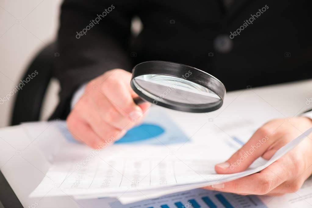 Businessman reading documents with magnifying glass concept for 