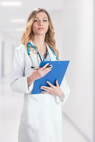 Female doctor in white surgical coat with stethoscope standing o