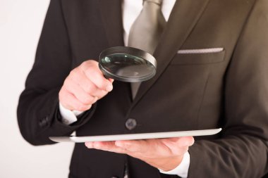 Büyüteç ile bir tablet kontrol işadamı 