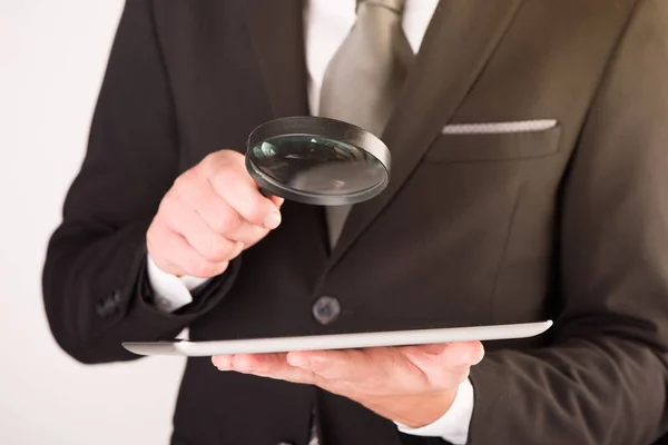 Zakenman controleren een tablet met Vergrootglas — Stockfoto