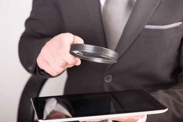 Zakenman controleren een tablet met Vergrootglas — Stockfoto