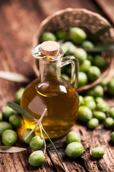 Bottle of olive oil and olves on wooden table