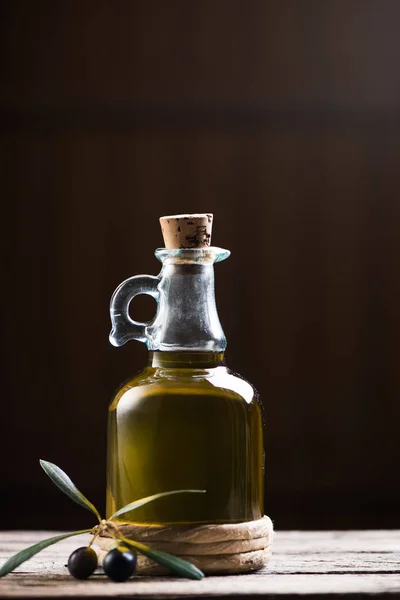 Botella de aceite de oliva y olivos sobre mesa de madera — Foto de Stock