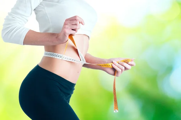 Slim young woman measuring her thin waist with a tape measure — Stock Photo, Image