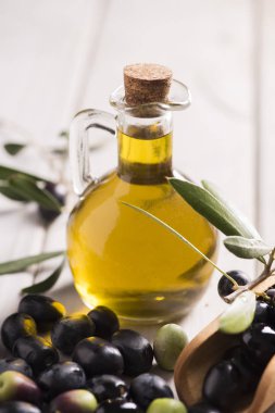 Zeytin ve zeytinyağı beyaz koyu ahşap masa üzerinde bir şişe