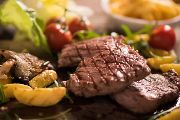 Carne a la parrilla con hierbas sobre tabla de madera —  Fotos de Stock